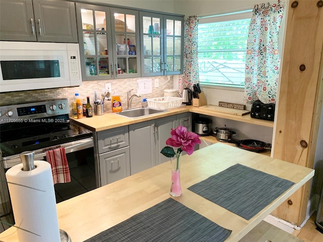 kitchen featuring tasteful backsplash, stainless steel electric range oven, gray cabinetry, and sink