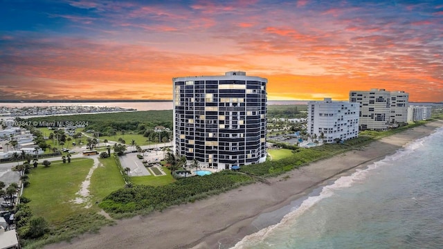 aerial view at dusk with a water view and a beach view