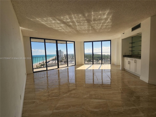 spare room with a water view, a healthy amount of sunlight, and a textured ceiling