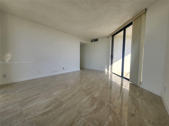 spare room with a wall of windows and a textured ceiling