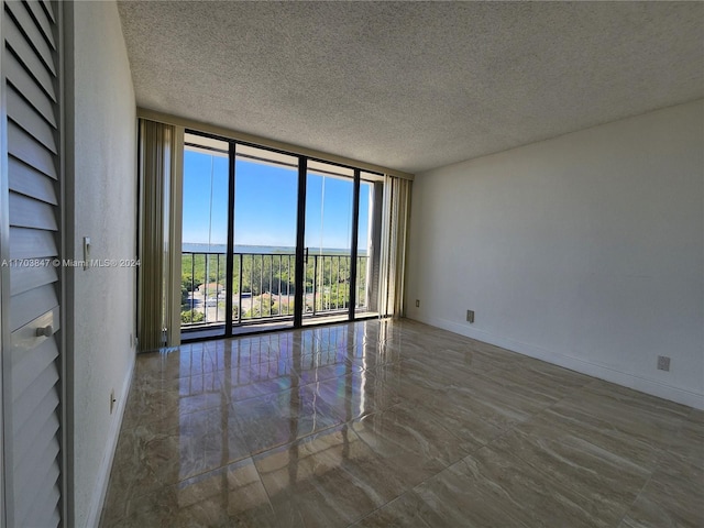 spare room with a textured ceiling and a wall of windows