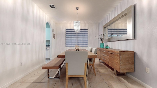 tiled dining room with a chandelier