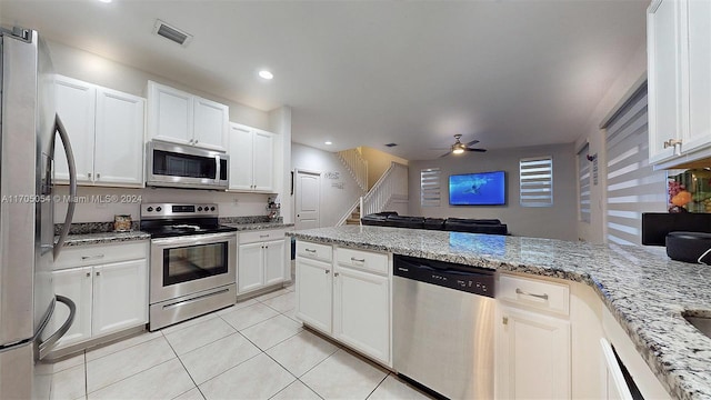 kitchen featuring appliances with stainless steel finishes, light stone counters, ceiling fan, light tile patterned floors, and white cabinets