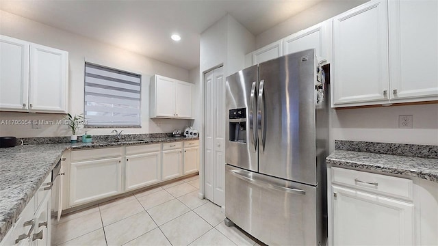 kitchen with white cabinets, stainless steel fridge with ice dispenser, dark stone counters, and light tile patterned flooring