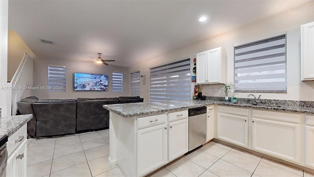 kitchen with kitchen peninsula, stainless steel dishwasher, sink, stone countertops, and white cabinetry