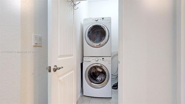 clothes washing area with light tile patterned floors and stacked washing maching and dryer