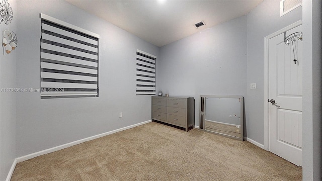 unfurnished bedroom with light colored carpet and lofted ceiling