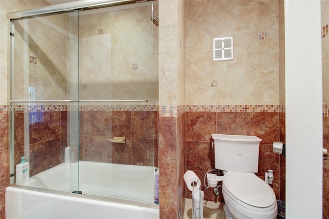 bathroom featuring shower / bath combination with glass door, tile walls, and toilet