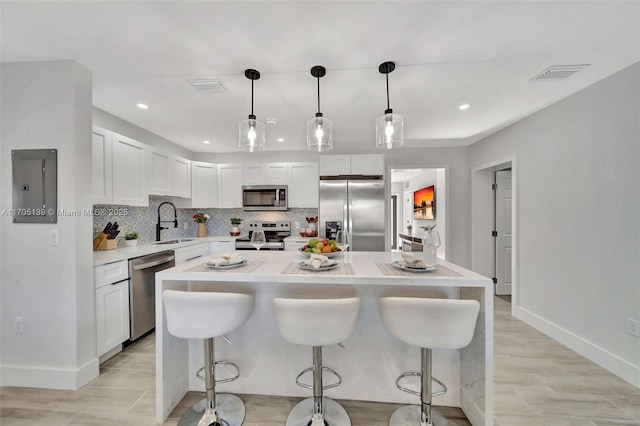 kitchen featuring sink, white cabinetry, hanging light fixtures, stainless steel appliances, and a kitchen island