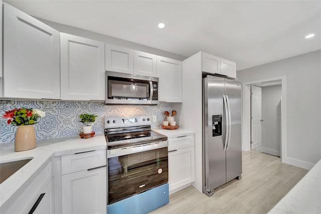 kitchen featuring white cabinetry, appliances with stainless steel finishes, light stone counters, and decorative backsplash