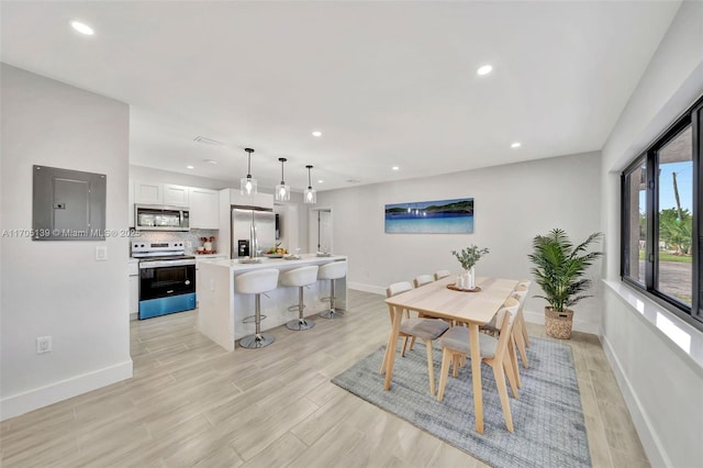 dining space featuring electric panel and light wood-type flooring