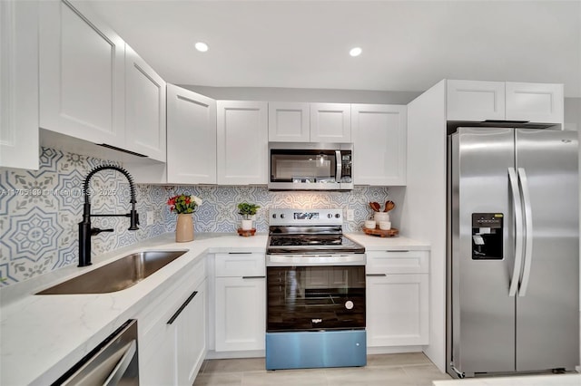 kitchen featuring stainless steel appliances, light stone countertops, sink, and white cabinets