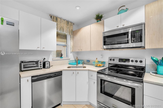 kitchen featuring stainless steel appliances, white cabinetry, and sink