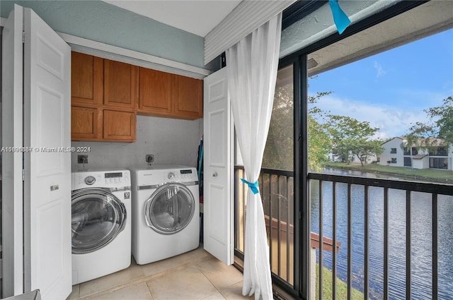 washroom featuring cabinets, a water view, light tile patterned floors, and washing machine and clothes dryer