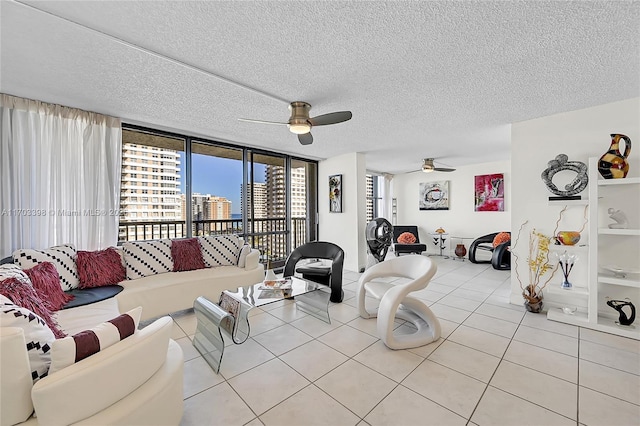 living room featuring floor to ceiling windows, ceiling fan, light tile patterned floors, and a textured ceiling