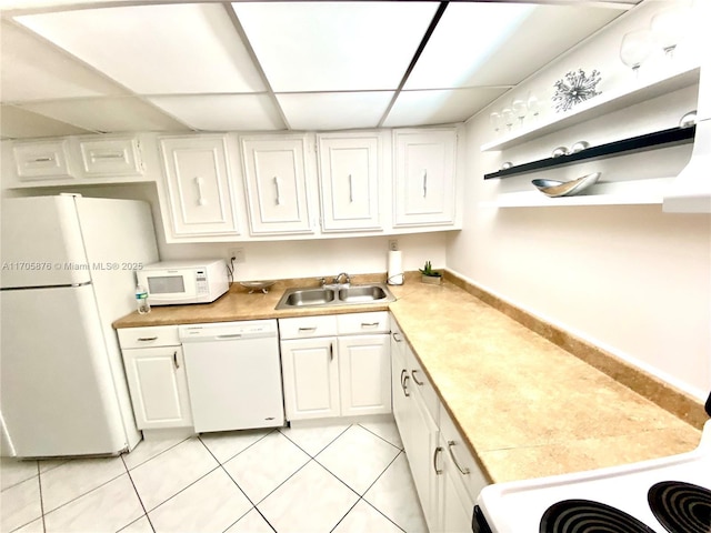 kitchen with white appliances, white cabinets, light tile patterned flooring, and a sink