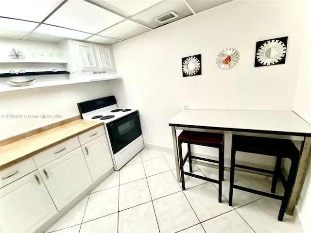 kitchen featuring visible vents, under cabinet range hood, a drop ceiling, range with electric stovetop, and white cabinets