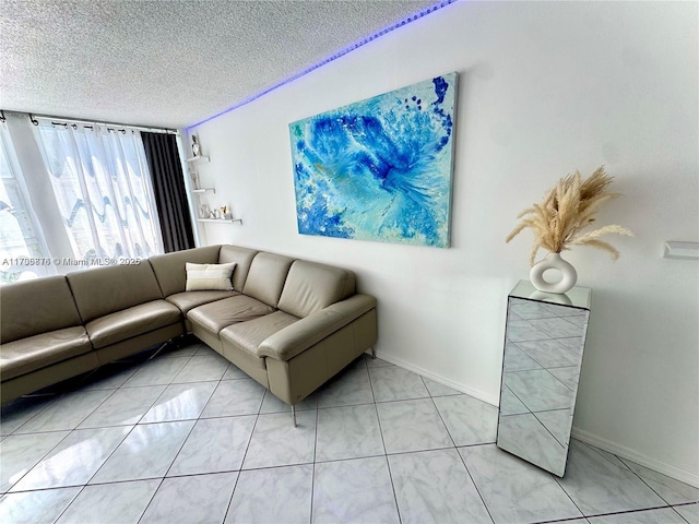 living room featuring light tile patterned floors, baseboards, and a textured ceiling