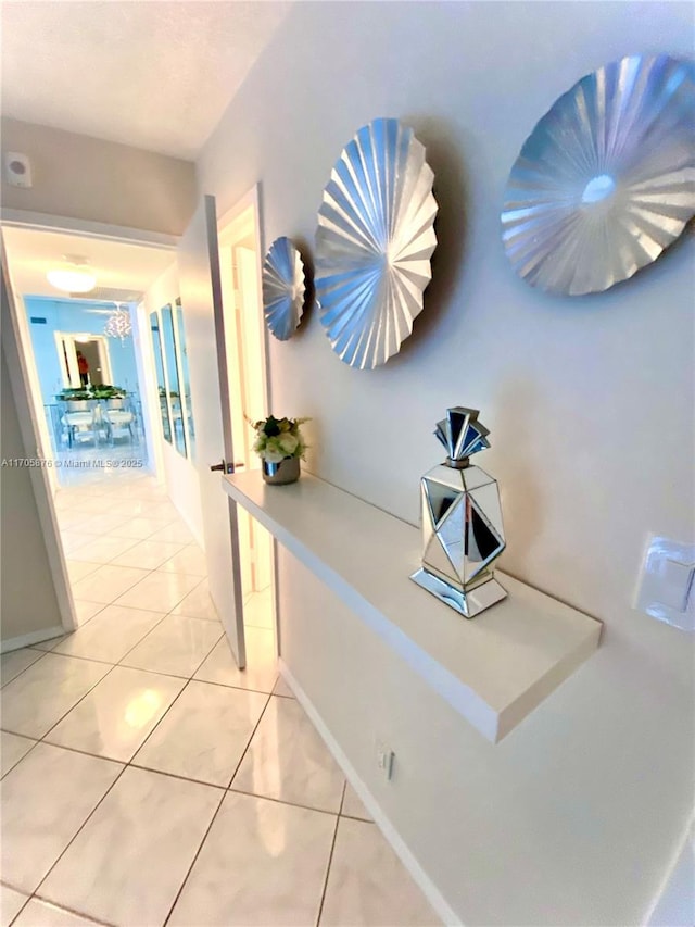 hallway featuring light tile patterned floors and baseboards