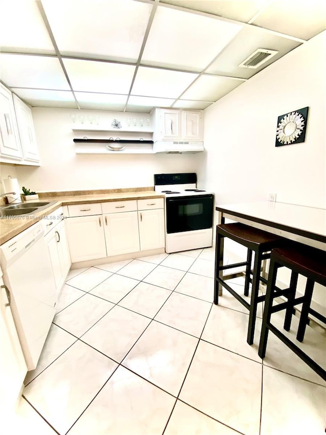 kitchen with white appliances, white cabinetry, a drop ceiling, and sink