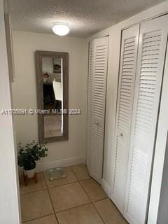 hallway featuring a textured ceiling and light tile patterned flooring