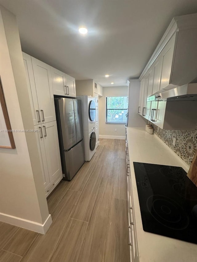 kitchen featuring black electric stovetop, light hardwood / wood-style floors, white cabinetry, and stainless steel refrigerator