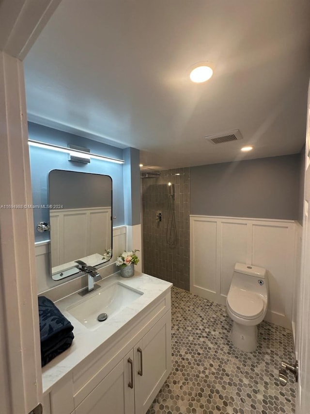 bathroom featuring a tile shower, tile patterned floors, vanity, and toilet