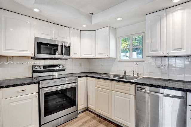 kitchen with light wood-type flooring, white cabinetry, sink, and appliances with stainless steel finishes