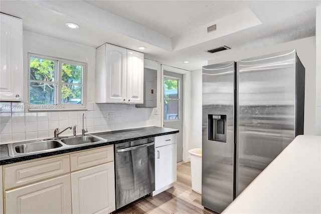 kitchen with plenty of natural light, white cabinets, hardwood / wood-style floors, and appliances with stainless steel finishes