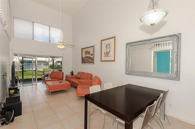 dining space featuring ceiling fan, light tile patterned floors, and a high ceiling