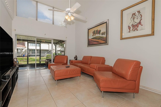 living room featuring ceiling fan, light tile patterned floors, and a high ceiling