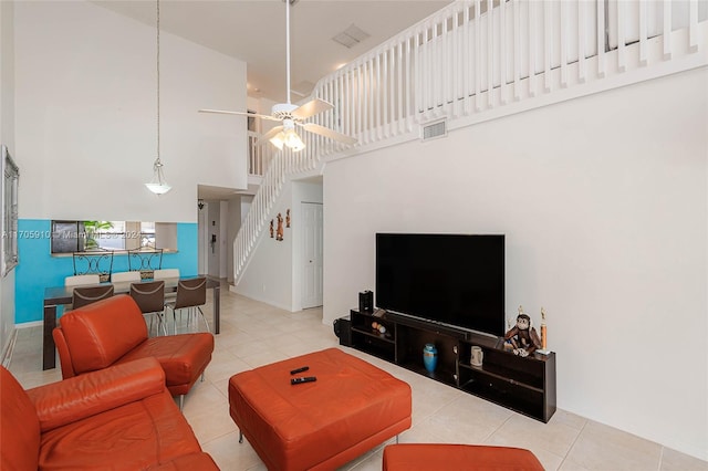 living room featuring ceiling fan, light tile patterned flooring, and a towering ceiling