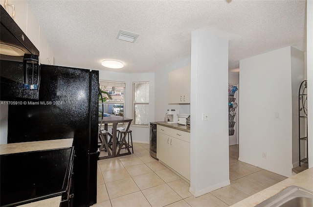 kitchen with light tile patterned flooring, white cabinetry, and a textured ceiling