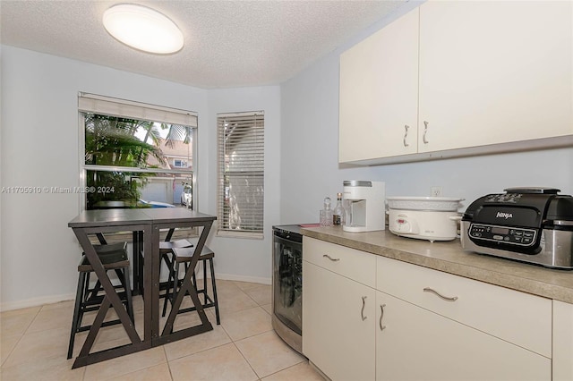 kitchen featuring white cabinetry, light tile patterned floors, a textured ceiling, and washer / dryer