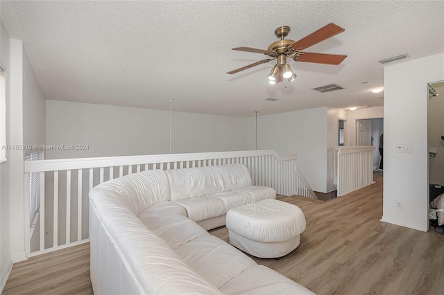 living room featuring wood-type flooring, a textured ceiling, and ceiling fan