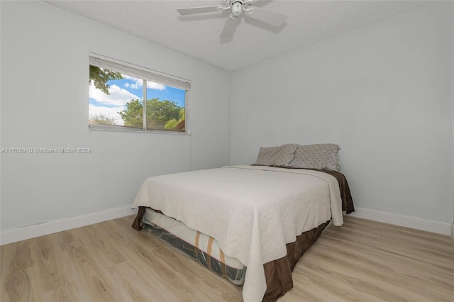 bedroom with ceiling fan, light hardwood / wood-style floors, and a textured ceiling