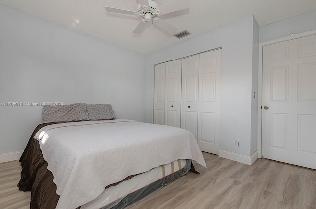 bedroom with a closet, ceiling fan, light hardwood / wood-style flooring, and a textured ceiling