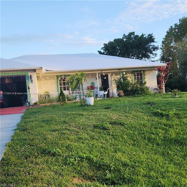 single story home with covered porch, a garage, and a front yard