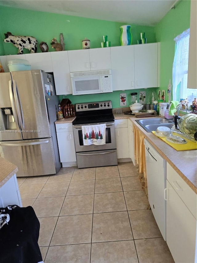 kitchen with white cabinets, appliances with stainless steel finishes, light tile patterned floors, and sink