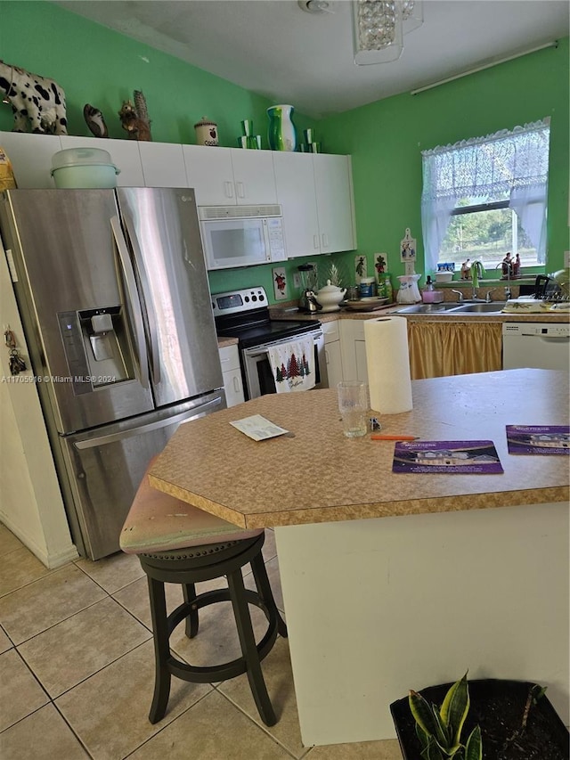 kitchen featuring white cabinets, a kitchen breakfast bar, stainless steel appliances, and light tile patterned flooring