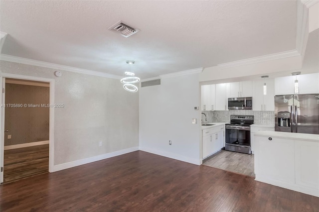 kitchen featuring appliances with stainless steel finishes, pendant lighting, sink, white cabinetry, and backsplash