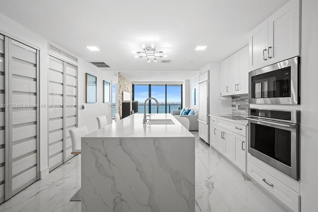 460 NE 28th St Unit 3205, Miami, FL 33137 - kitchen with built in appliances, light marble finish flooring, a water view, open floor plan, and a kitchen island with sink