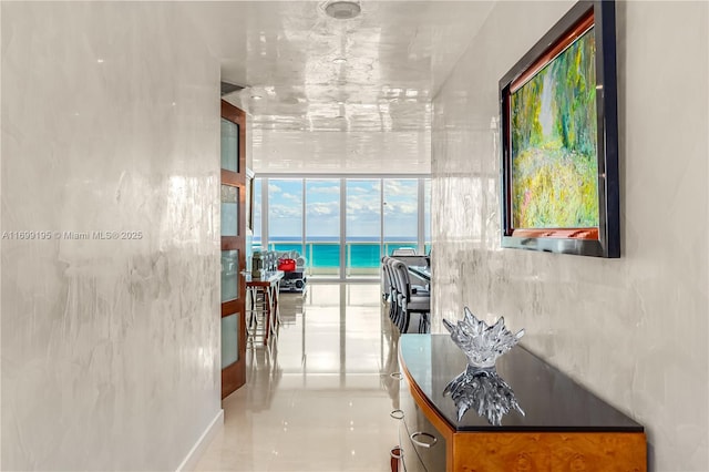 corridor featuring tile patterned flooring, floor to ceiling windows, and a water view