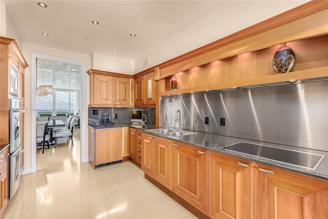 kitchen featuring dark stone counters, recessed lighting, stainless steel appliances, a sink, and backsplash