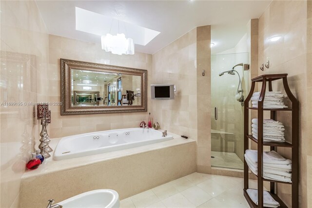 bathroom with a skylight, a stall shower, tile walls, and a garden tub