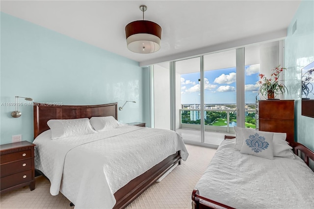 bedroom featuring access to exterior, floor to ceiling windows, light colored carpet, and visible vents