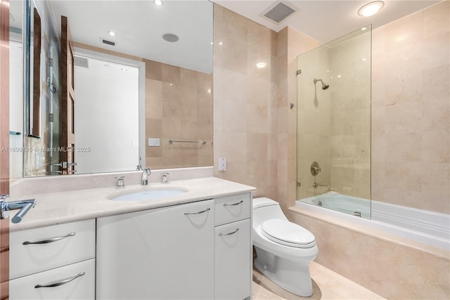 full bathroom featuring visible vents, toilet, vanity, tile walls, and tiled shower / bath