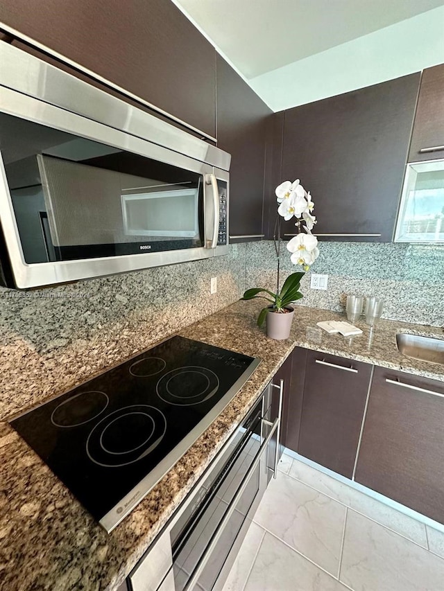 kitchen with tasteful backsplash, dark brown cabinets, black electric stovetop, and stone countertops