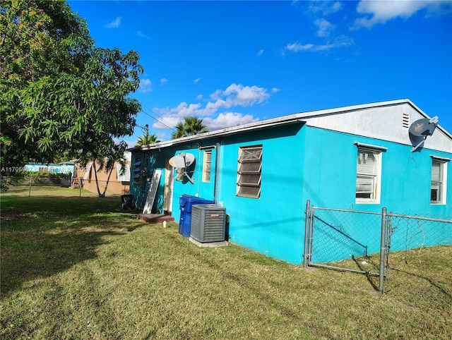 view of side of property with central AC and a lawn