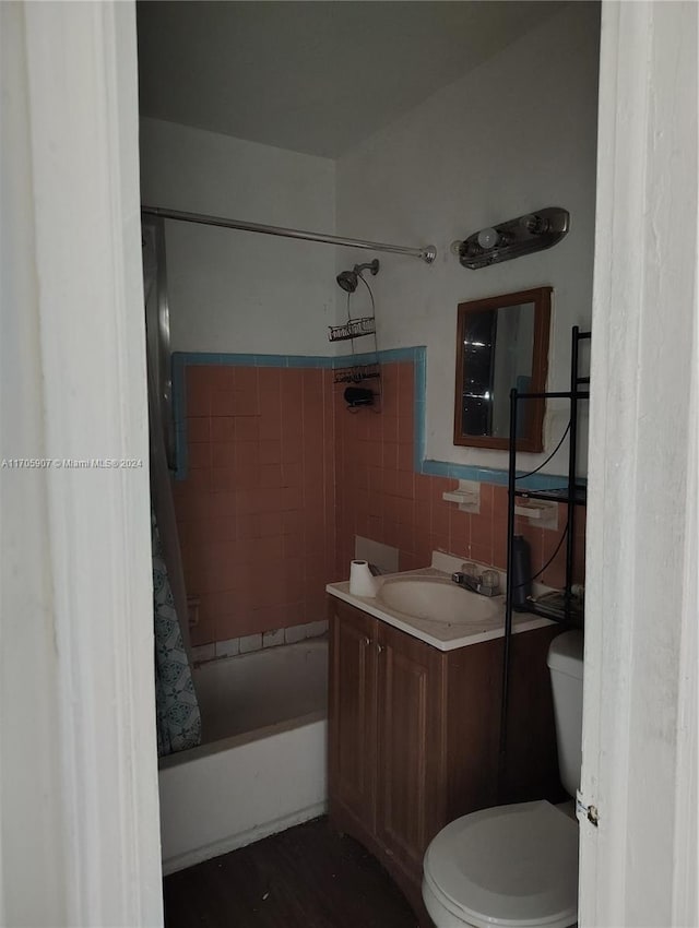 full bathroom with vanity, toilet, shower / bath combo with shower curtain, and tile walls